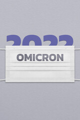 Poster with paper figurines 2022 under an unused  face mask with the inscription Omicron.
