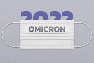 Face mask with the inscription Omicron on the background of paper figure 2022. 