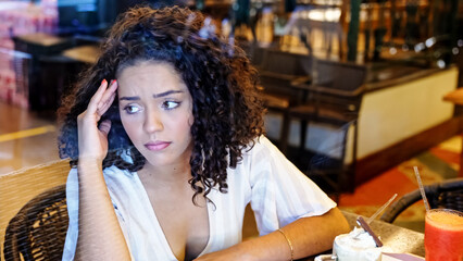 Depressed sad latin woman in bakery. Looking at the horizon, worried. End of relationship