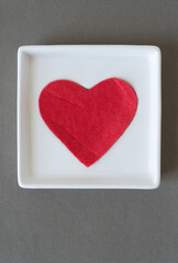 red felt heart on a white dish viewed from above