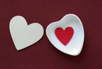 Obraz premium heart shaped dish with wooden hearts on red brown fabric