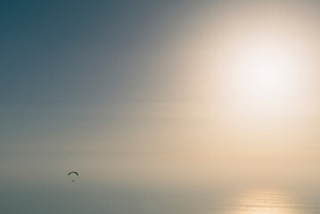 Paragliding over the sea at sunset