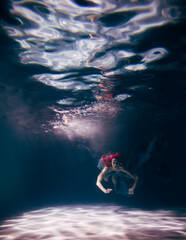 Fototapeta premium Young woman underwater in a beautiful dress underwater shooting