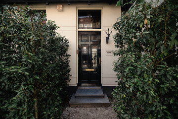 Beautiful facade of the house in thickets of bushes. Black door and surrounding architecture,...