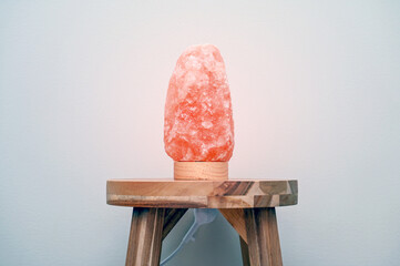 Himalayan salt lamp on wood table near neutral wall