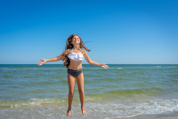 Fototapeta na wymiar Flying jump beach little happy girl on blue sea shore in summer vacation