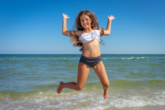 Flying jump beach little happy girl on blue sea shore in summer vacation