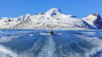 Motor boat in the middle of Nuuk fjord with frozen rocks in the background, Greenland