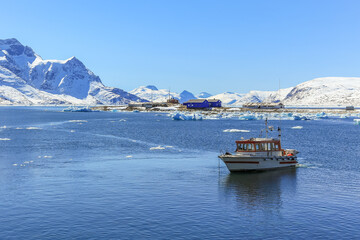 Boat anchored in the lagoon and Qoornoq former fishermen village in the middle of Nuuk fjord, Greenland