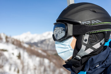 ski resort man on chairlift in helmet and medical mask