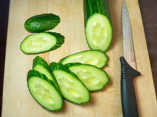 A smooth, medium-sized cucumber cut into slices. Cucumber on a cutting board. Vegetable isolate. Fresh ripe vegetable