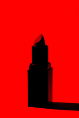 Lipstick tube on red background. Silhouette of pomade