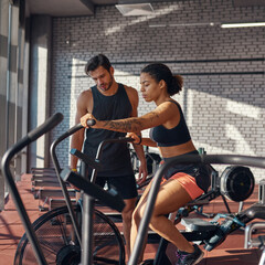 Obraz premium Trainer looking at orbitrek while woman exercising