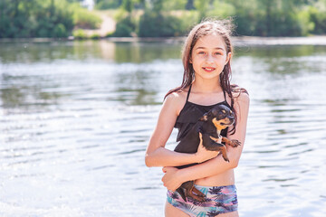 A beautiful girl stands at the beginning of the river with a Chihuahua dog. Child and dog. Pet.