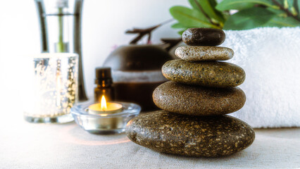 Beauty and relaxation treatment in a spa. Essential oils, massage stones on a light table in a very bright environment. CopySpace.