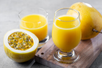Glass with passion fruit juice and sliced ​​passion fruit on the table.