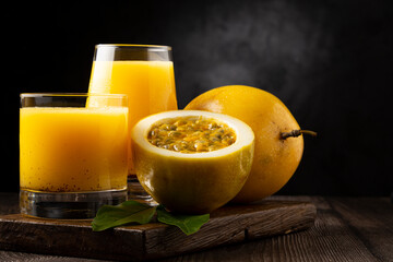 Glass with passion fruit juice and sliced ​​passion fruit on the table.