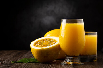 Glass with passion fruit juice and sliced ​​passion fruit on the table.