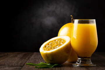 Glass with passion fruit juice and sliced ​​passion fruit on the table.