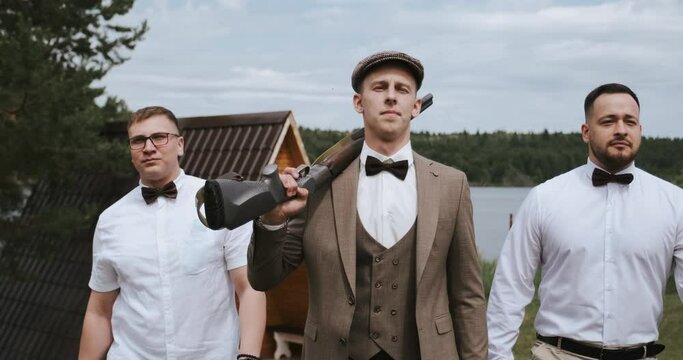 Group of three men friends gangsters, central man carries a gun on his shoulder. Gang band of cool guys gangsta. Retro american vintage style