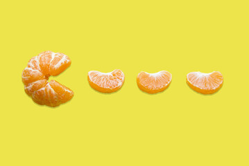 Mandarin and mandarin slice on a yellow background. Pacman game. Tangerine Pacman. Vitamin C