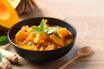 Thai spicy pumpkin curry soup with pork on wooden table