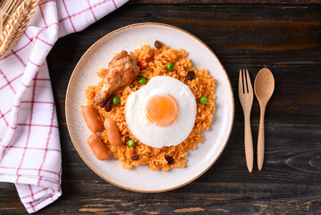 Fried rice with chicken, sausage and fried egg on wooden background, Table top view