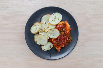 A plate of grilled chicken with sliced potatoes.