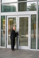 Businessman entering an office building and smiling over his shoulder