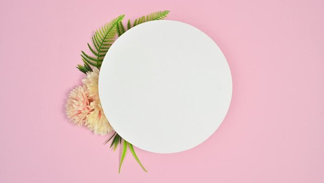 White paper for text and spring flowers appear around on pastel pink theme. Stop motion