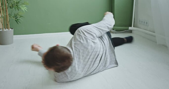 Active nervous man moving on floor. Anxious impatient male lying on floor and moving fast in circle like running while feeling concern and looking at camera