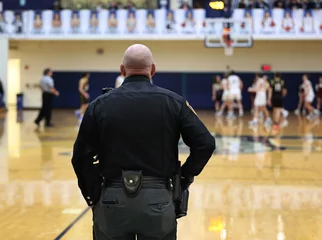 Foto auf Acrylglas A police officer watches a high school basketball game © Ron Alvey