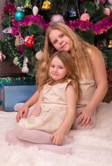 Two beautiful little sisters near the Christmas tree.