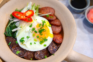Chinese sausage Stir-fried Rice with a fried egg delicious Chinese food served in a white clay pot, selective focus.