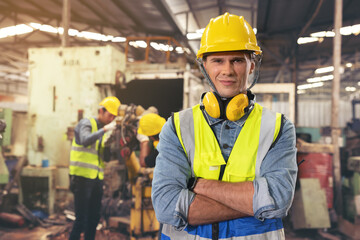 Portrait of a bearded factory worker in a hardhat staring at the photo while standing in a...