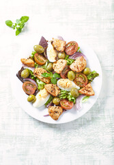 Salad with green olives, cherry tomatoes, chicken and eggs. Bright wooden background. Top view.