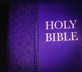 A royal blue, leather-bound printed copy of the King James version of the Holy Bible against a black backdrop