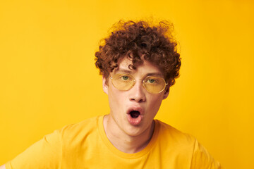 Young curly-haired man Youth style glasses studio casual wear yellow background unaltered