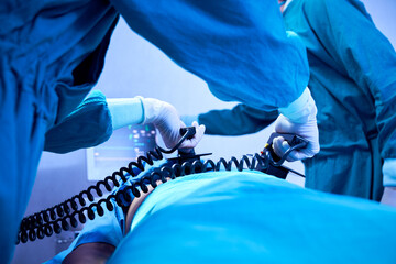 Doctor holding defibrillator paddles in both hands prepare help patient in operating room at hospital
