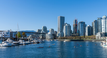 Fototapeta na wymiar Vancouver, BC, Canada - April 16 2021 : Vancouver marina, False Creek, modern buildings skyline in the background. Granville Bridge.