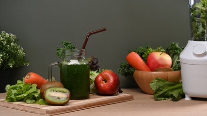 Healthy green smoothie with fruits and vegetables on wooden table.