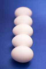 Five white raw eggs lie on the table. Vertical photo, large eggs. Preparing for Easter. Easter Ingredients