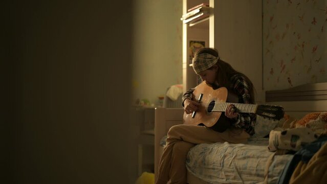 young girl playing guitar at home bedroom