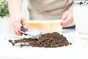 A woman's hands with a shovel take the earth and put it in a pot for flowers. Horizontal view.