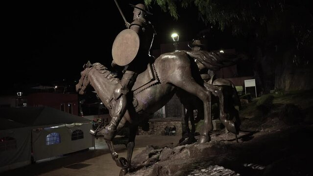 Statue of a Mexican soldier riding a horse in town at night 