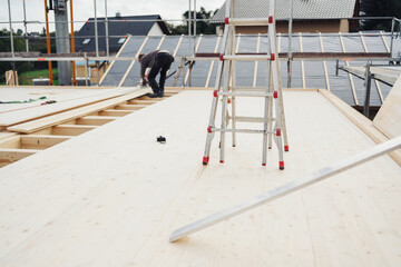 Builders ladder and workman on a new build rooftop