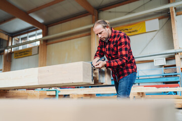 Carpenter in a woodworking workshop of factory drilling a hole