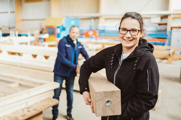 Happy friendly young female worker in a woodworking factory