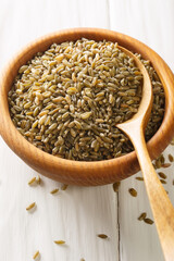 healthy uncooked cracked freekeh grain in the bowl on white rustic table. Vertical