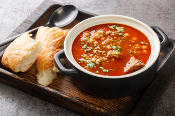 Traditional soup Chorba Frik made from lamb, Freekeh and vegetables close-up in a plate on the...